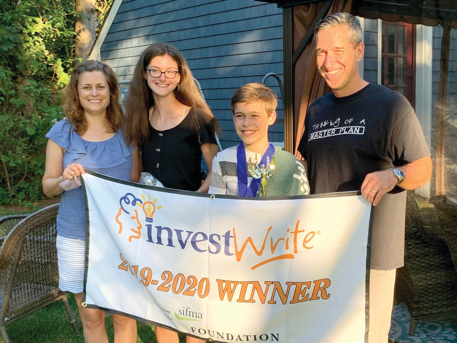 Evan Gendreau of Seekonk, Mass., smiles with his parents, Michael and Melanie, and sister Kelsey. The family was surprised at their home by Gendreau’s teacher Laura Doliber and St. Margaret School Principal Lee Ann Nunes, who informed Evan that he had won the National InvestWrite® Competition.